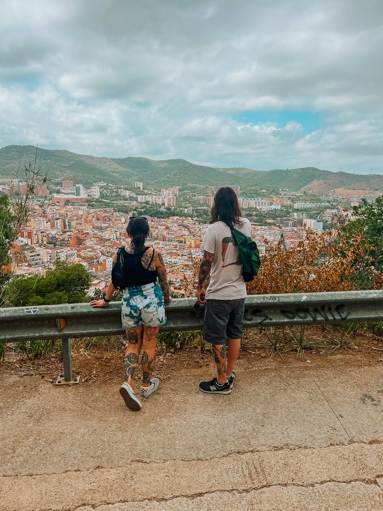 Couple overlooks sprawling Barcelona cityscape from a scenic viewpoint.