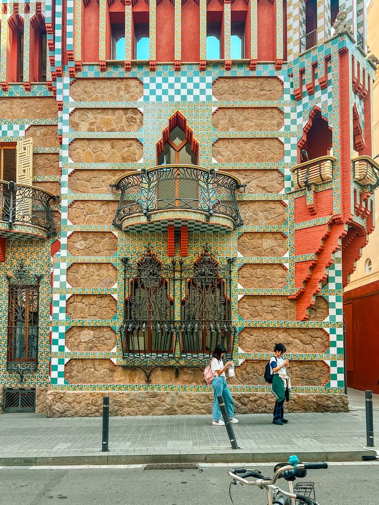 Casa Vicens, a colorful modernist building in Barcelona, with two people walking by.