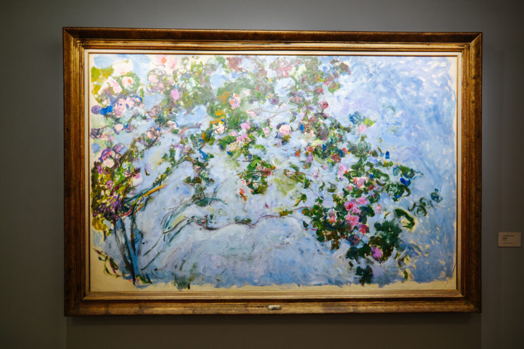 Monet's impressionist painting of blooming pink roses and blue sky